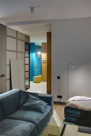 Luminous interior in a modern style with gray and blue walls. There is glowing lamps, sofa and a pouf with a plaid, hallway with a wooden wardrobe, mirror, yellow pouf and a glass partition. Vertical. Stock Photo - Budget Royalty-Free & Subscription, Code: 400-08832534