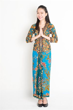 Portrait of young southeast Asian woman in traditional Malay batik kebaya dress greeting, full length standing on plain background. Stock Photo - Budget Royalty-Free & Subscription, Code: 400-08832764