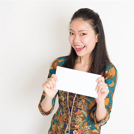 Portrait of young southeast Asian girl in traditional Malay batik kebaya dress hand holding a white blank paper card with surprised face expression, standing on plain background. Stock Photo - Budget Royalty-Free & Subscription, Code: 400-08832765