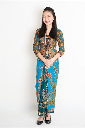 Portrait of young southeast Asian girl in traditional Malay batik kebaya dress smiling, full length standing on plain background. Stock Photo - Budget Royalty-Free & Subscription, Code: 400-08832766
