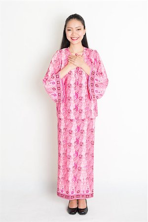 Portrait of young southeast Asian woman in traditional Malay batik dress greeting, standing on plain background. Stock Photo - Budget Royalty-Free & Subscription, Code: 400-08832761