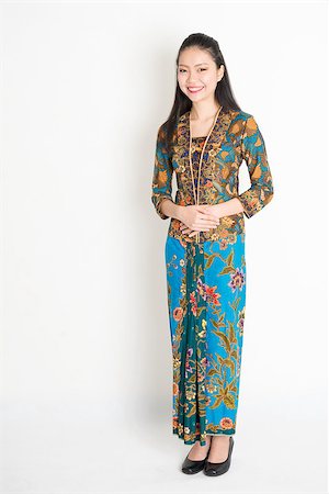 Portrait of young southeast Asian woman in traditional Malay batik kebaya dress smiling, full length standing on plain background. Stock Photo - Budget Royalty-Free & Subscription, Code: 400-08832762