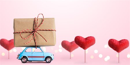 Blue retro toy car delivering gift box for Valentine's day on pink background with heart trees Stock Photo - Budget Royalty-Free & Subscription, Code: 400-08864809