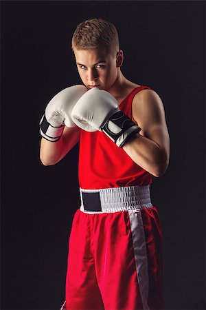 simsearch:400-04922500,k - Young handsome boxer sportsman in red boxer suit and white gloves standing on black backgound. Copy space. Photographie de stock - Aubaine LD & Abonnement, Code: 400-08861358