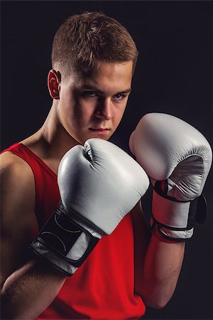 simsearch:400-04922500,k - Young handsome boxer sportsman in red boxer suit and white gloves standing on black backgound. Copy space. Photographie de stock - Aubaine LD & Abonnement, Code: 400-08861360