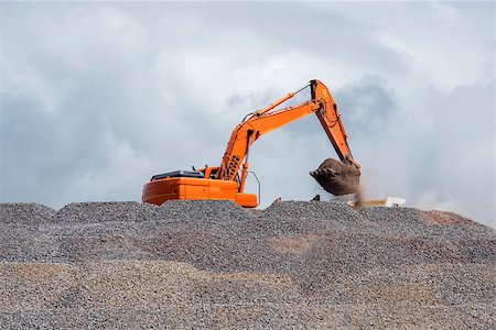 A big digger on a mountain of stone loads up a truck with material. Photographie de stock - Aubaine LD & Abonnement, Code: 400-08861719