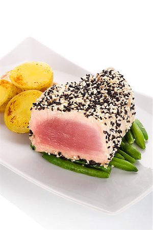simsearch:400-05204133,k - Grilled tuna steak wrapped in black and white sesame seeds on green beans with potatoes on white plate on white background. Culinary seafood eating. Stock Photo - Budget Royalty-Free & Subscription, Code: 400-08861886