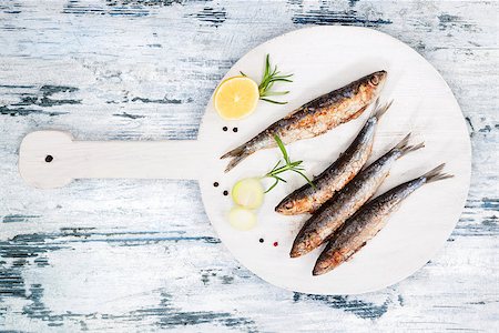 simsearch:400-08070549,k - Delicious grilled sardines on wooden kitchen board on white and blue wooden textured background. Culinary seafood eating. Stockbilder - Microstock & Abonnement, Bildnummer: 400-08862547