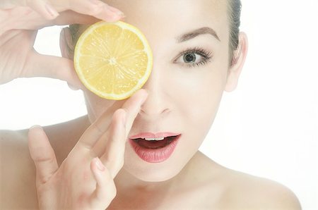 Portrait of a  young woman with one halves of a lemon near the lips. Mouth open. Hands near the face. Horizontal photo Stock Photo - Budget Royalty-Free & Subscription, Code: 400-08863167