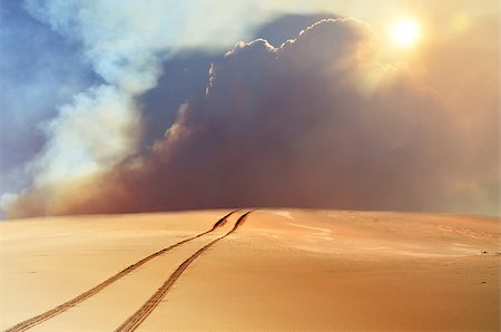 smoke dust - Vehicle tracks through desert and dunes leading into a sand, smoke and cloud filled sky. Digital photo manipulation. Stock Photo - Budget Royalty-Free & Subscription, Code: 400-08888113