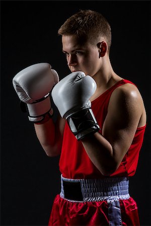 simsearch:400-04922500,k - Young handsome boxer sportsman in red boxer suit and white gloves standing on black backgound. Copy space. Photographie de stock - Aubaine LD & Abonnement, Code: 400-08888259