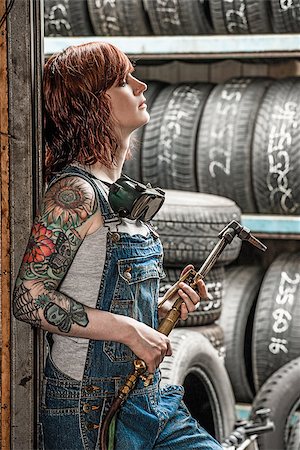 Photo of a beautiful redhead female mechanic with tattoos holding a welding torch. Foto de stock - Super Valor sin royalties y Suscripción, Código: 400-08888368