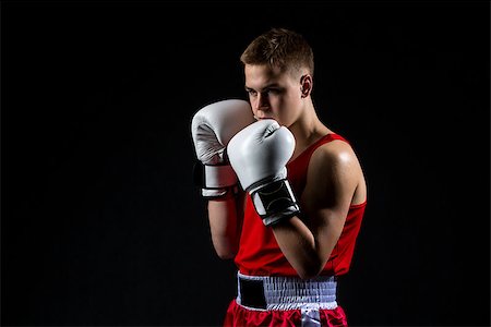 simsearch:400-04922500,k - Young handsome boxer sportsman in red boxer suit and white gloves standing on black backgound. Copy space. Photographie de stock - Aubaine LD & Abonnement, Code: 400-08888827