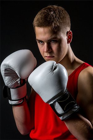 simsearch:400-04922500,k - Young handsome boxer sportsman in red boxer suit and white gloves standing on black backgound. Copy space. Photographie de stock - Aubaine LD & Abonnement, Code: 400-08888828