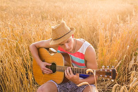 simsearch:400-05080507,k - Young man is playing guitar in the field. Stock Photo - Budget Royalty-Free & Subscription, Code: 400-08888881