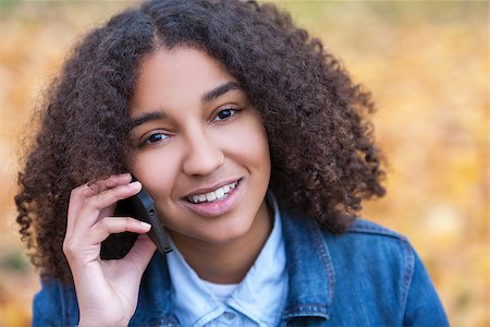 simsearch:400-04068097,k - Outdoor portrait of beautiful happy mixed race African American girl teenager female young woman smiling with perfect teeth talking on cell phone Stockbilder - Microstock & Abonnement, Bildnummer: 400-08889152