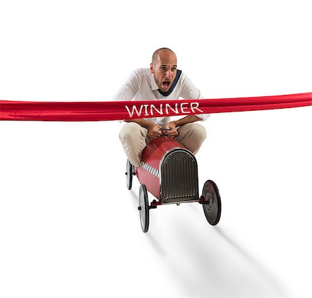 simsearch:632-05603965,k - Businessman drives a toy car beyond the red ribbon at the arrival of a race Fotografie stock - Microstock e Abbonamento, Codice: 400-08899935