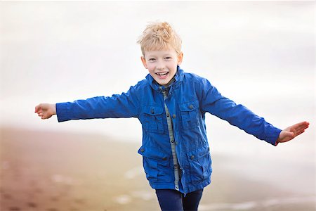 excited smiling boy in warm clothes running at the beach in california Stock Photo - Budget Royalty-Free & Subscription, Code: 400-08891195