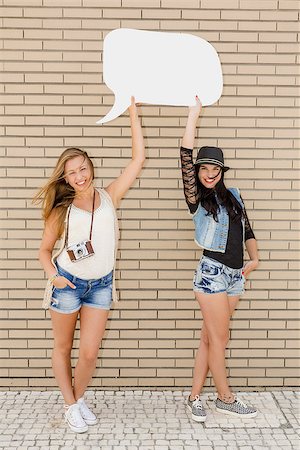 female models balloons - Two beautiful and young girlfriends holding a thought balloon, in front of a brick wall Stock Photo - Budget Royalty-Free & Subscription, Code: 400-08891317