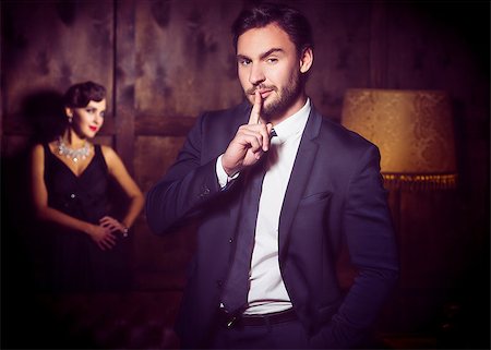 Wealth, luxury concepts. Handsome man keep secret and keeping hand in pocket. Beautiful lady stay on background. Stock Photo - Budget Royalty-Free & Subscription, Code: 400-08891329