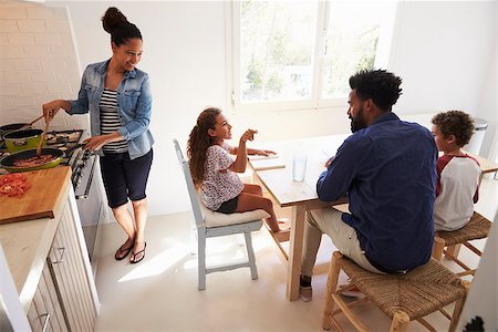 Dad helping kids with homework and mum cooks, elevated view Photographie de stock - Aubaine LD & Abonnement, Code: 400-08891935