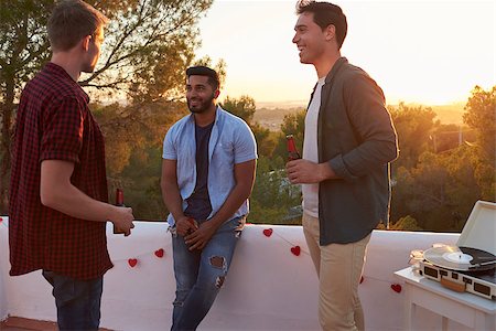 sunset drinking beer - Three male friends talk at a party on a rooftop at sunset Stock Photo - Budget Royalty-Free & Subscription, Code: 400-08892186