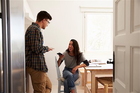 simsearch:400-08892339,k - Two teenage friends using smartphones, talking in kitchen Stock Photo - Budget Royalty-Free & Subscription, Code: 400-08892273