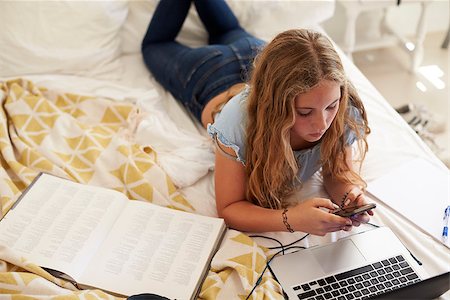 simsearch:400-08892339,k - Girl lying on bed using smartphone and laptop, high angle Stock Photo - Budget Royalty-Free & Subscription, Code: 400-08892335