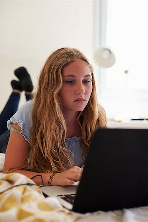 simsearch:400-08892339,k - Teenage girl using laptop lying on her bed, vertical Stock Photo - Budget Royalty-Free & Subscription, Code: 400-08892332