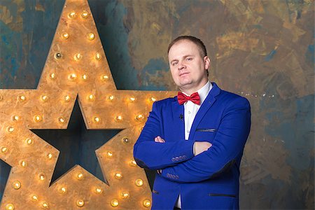 sashr (artist) - Happy elegant man in blue suit is standing with crossed hands at wall background Foto de stock - Super Valor sin royalties y Suscripción, Código: 400-08893299