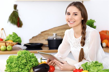 Young  woman is making online shopping by tablet computer. Housewife looking for a new recipe for  cooking in a kitchen Stock Photo - Budget Royalty-Free & Subscription, Code: 400-08917842
