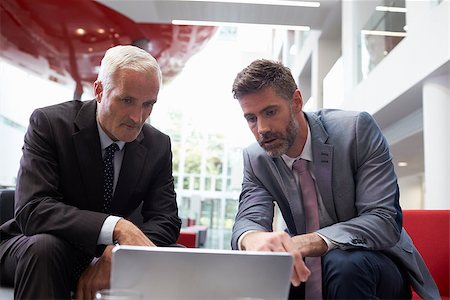 Two Businessmen Using Laptop In Lobby Area Of Modern Office Stock Photo - Budget Royalty-Free & Subscription, Code: 400-08937479