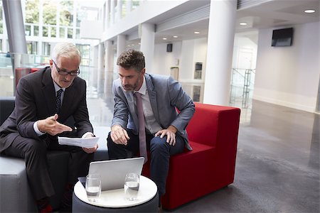 Two Businessmen Discuss Document In Lobby Of Modern Office Stock Photo - Budget Royalty-Free & Subscription, Code: 400-08937481