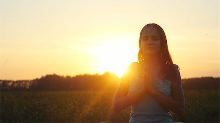 emaria (artist) - Young pretty brunette woman meditates in nature, in the field during sunset Fotografie stock - Microstock e Abbonamento, Codice: 400-08956435