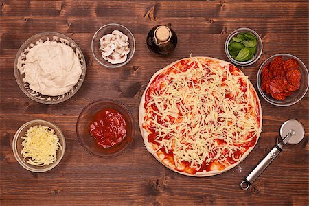 simsearch:400-08964146,k - Phases of making a pizza - putting on the grated cheese - top view of half made pizza and ingredients Stock Photo - Budget Royalty-Free & Subscription, Code: 400-08959158