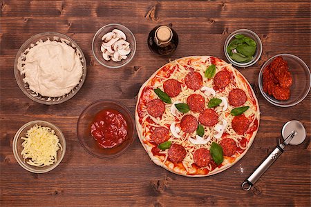 simsearch:400-08960199,k - Phases of making a pizza - the ready to bake pizza with ingredients around on a table, top view Stock Photo - Budget Royalty-Free & Subscription, Code: 400-08959159