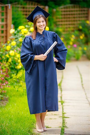 Smiling young woman holding diploma and wearing cap and gown outdoors looking at camera. Graduation concept. Foto de stock - Super Valor sin royalties y Suscripción, Código: 400-08966845