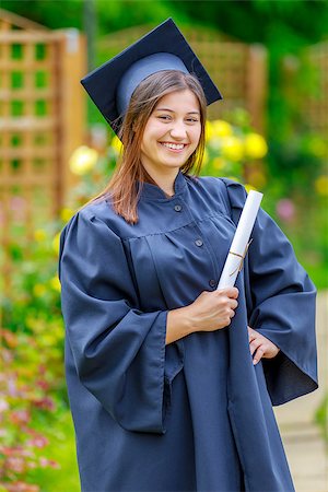 Smiling young woman holding diploma and wearing cap and gown outdoors looking at camera. Graduation concept. Foto de stock - Super Valor sin royalties y Suscripción, Código: 400-08966846