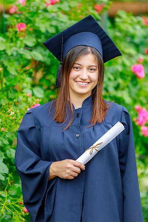 Smiling young woman holding diploma and wearing cap and gown outdoors looking at camera. Graduation concept. Foto de stock - Super Valor sin royalties y Suscripción, Código: 400-08966847