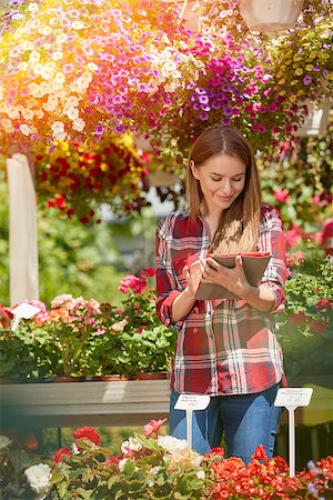 Smiling young female botanist using tablet standing near flowers in the garden in sunny day. Photographie de stock - Aubaine LD & Abonnement, Code: 400-08968131