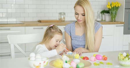 Beautiful woman and little girl sitting by table and coloring Easter eggs together at modern light kitchen. Stock Photo - Budget Royalty-Free & Subscription, Code: 400-08962177