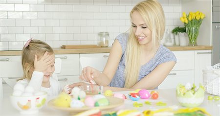 Laughing young mother and little adorable girl coloring Easter eggs together while sitting at table in kitchen. Stock Photo - Budget Royalty-Free & Subscription, Code: 400-08962184