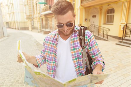 simsearch:649-06622240,k - Attractive hipster man in sunglasses looking at city map. Man in plaid shirt with backpack looking for directions. Toned image. Photographie de stock - Aubaine LD & Abonnement, Code: 400-08996959