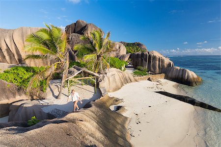 simsearch:400-06787807,k - Female traveler emjoying climbing ob beautifully shaped granite boulders at picture perfect tropical Anse Source d'Argent beach, La Digue island, Seychelles. Stock Photo - Budget Royalty-Free & Subscription, Code: 400-09008504