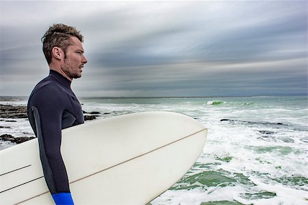 A side portrait of a surfer, with his surfboard under his arm as he views the ocean. Photographie de stock - Aubaine LD & Abonnement, Code: 400-09008528