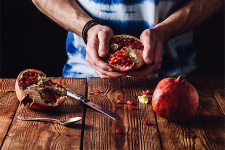 simsearch:400-08334670,k - Opened Pomegranate in the Hands. Other Half and Some Seeds on Table. Stock Photo - Budget Royalty-Free & Subscription, Code: 400-09008541