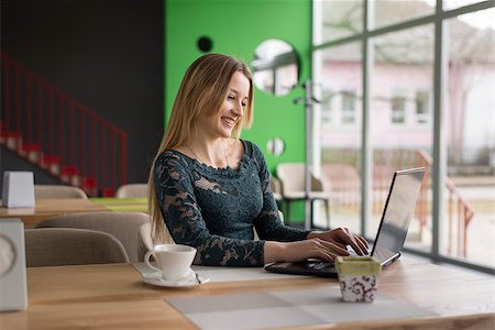 girl sitting in a café with a laptop and genuinely smiling Stockbilder - Microstock & Abonnement, Bildnummer: 400-09008574