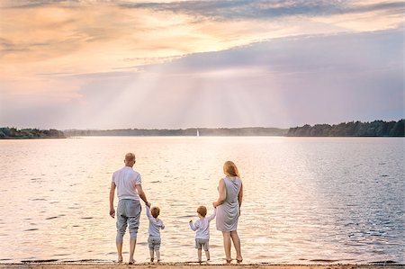 View from behind of happy family from mother, father and two boys watching the sunset and sailboat on the coast of lake. Concept of friendly family Stock Photo - Budget Royalty-Free & Subscription, Code: 400-09008804