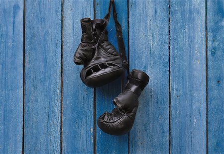 Black vintage boxing gloves hanging on an old rusty nail on a blue cracked wooden wall Stock Photo - Budget Royalty-Free & Subscription, Code: 400-09009818