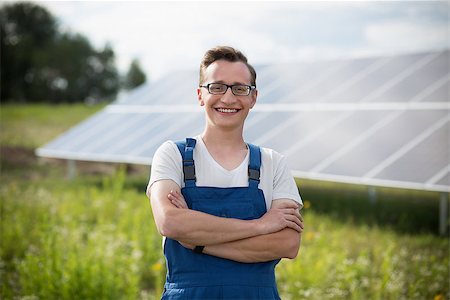 solar panels business - Worker standing in the field with solar with solar panels on backstage. Young man in glasses standing with his hands crossed. Stock Photo - Budget Royalty-Free & Subscription, Code: 400-09001291